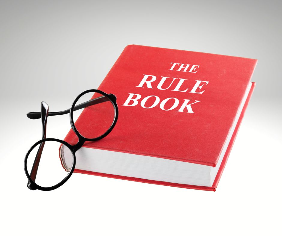 Red book saying The Rule Book with a pair of black glasses